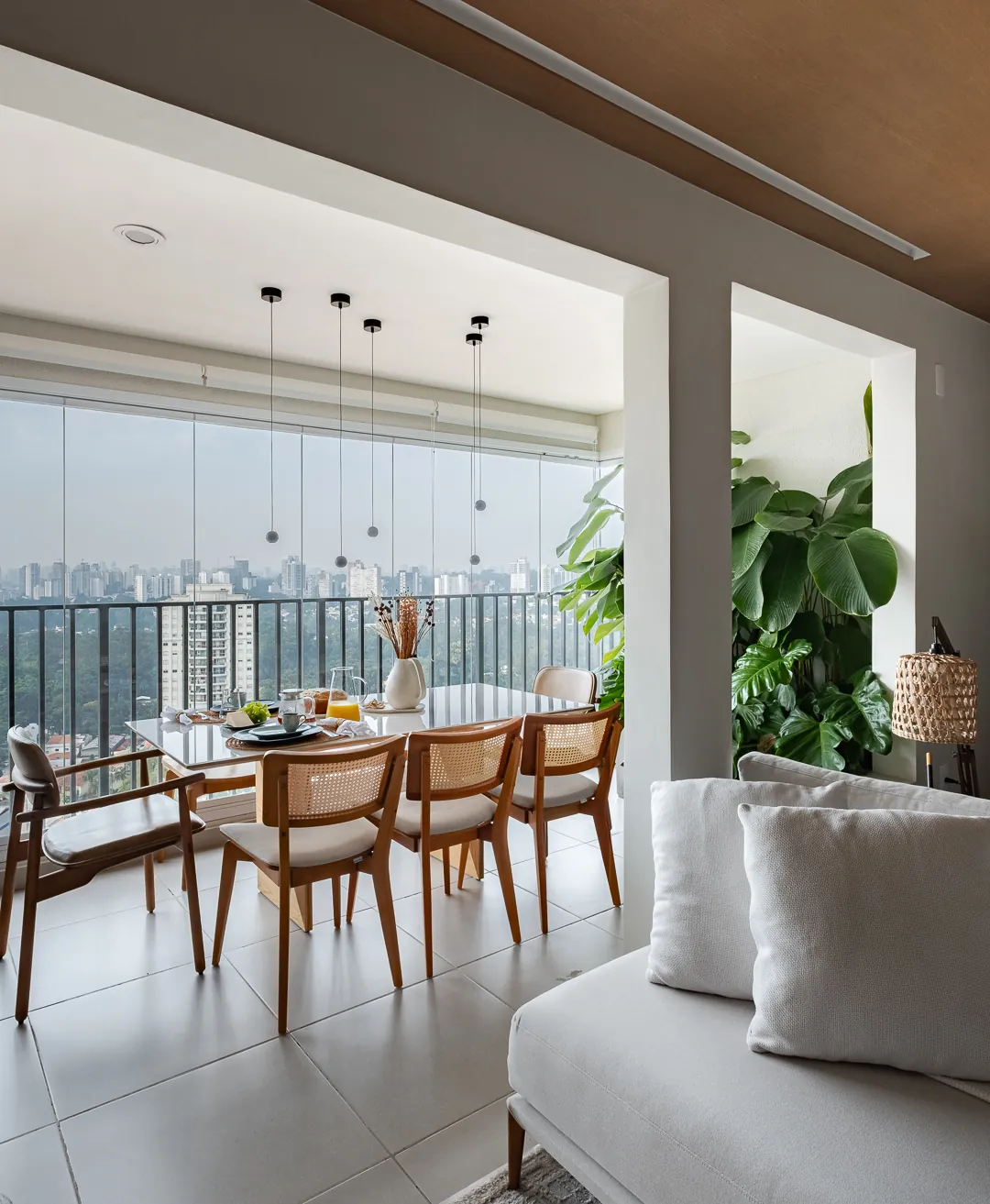 Mesa de jantar junto à varanda envidraçada com vista da cidade