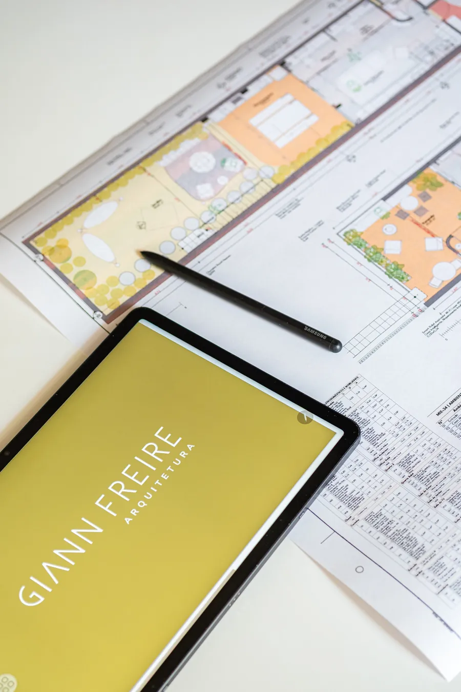 Tablet com o logotipo Giann Freire sobre plantas de projeto