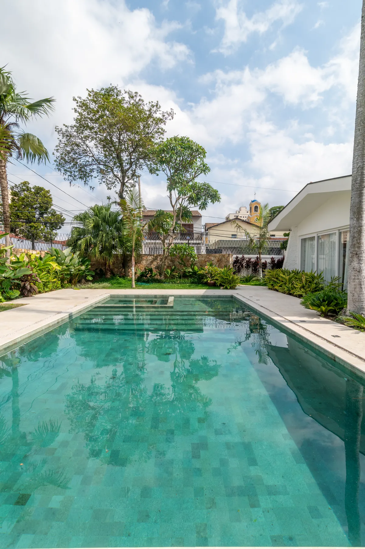 Piscina com borda clara e jardim tropical