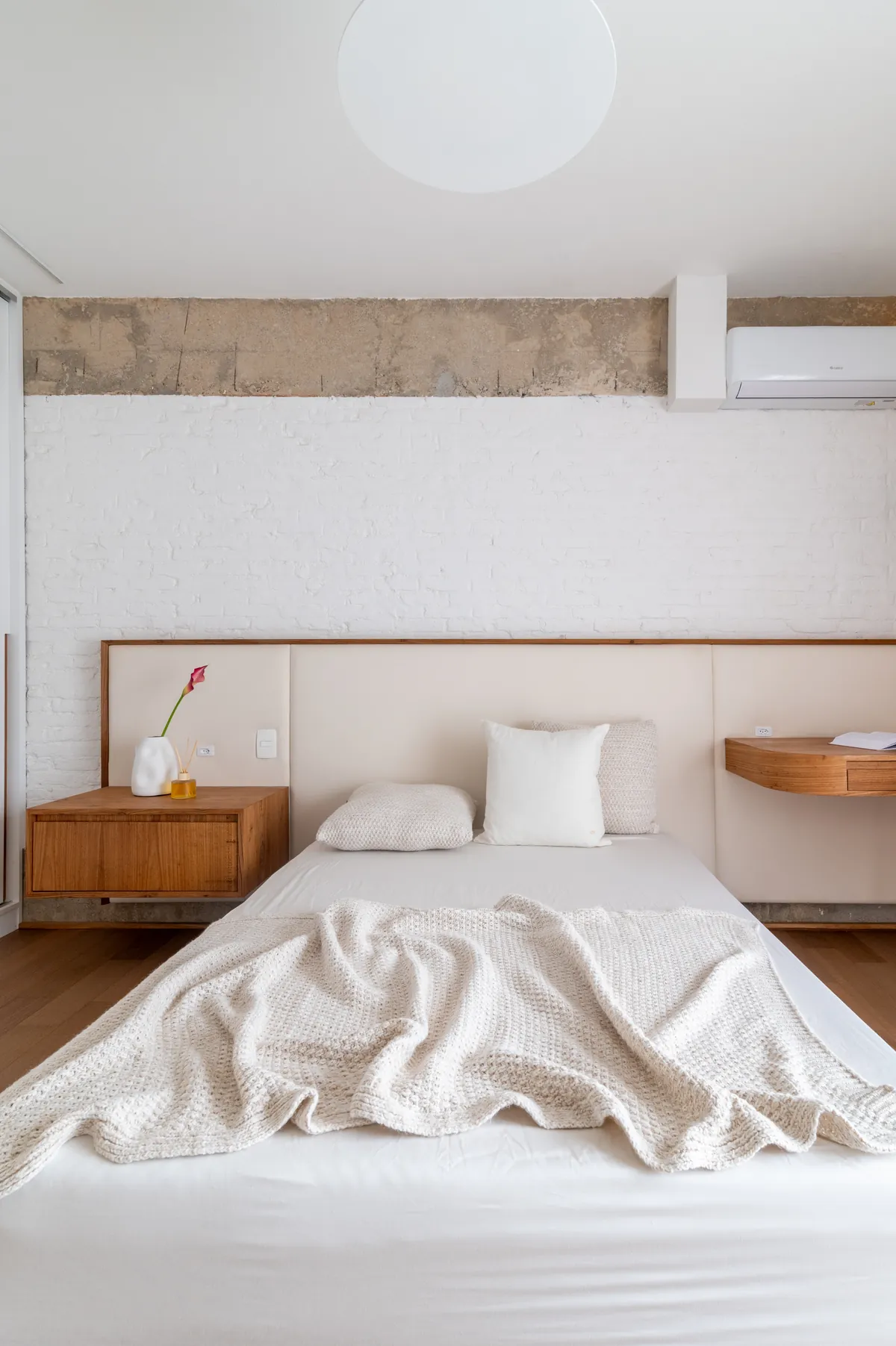 Quarto com cabeceira de madeira e roupa de cama clara