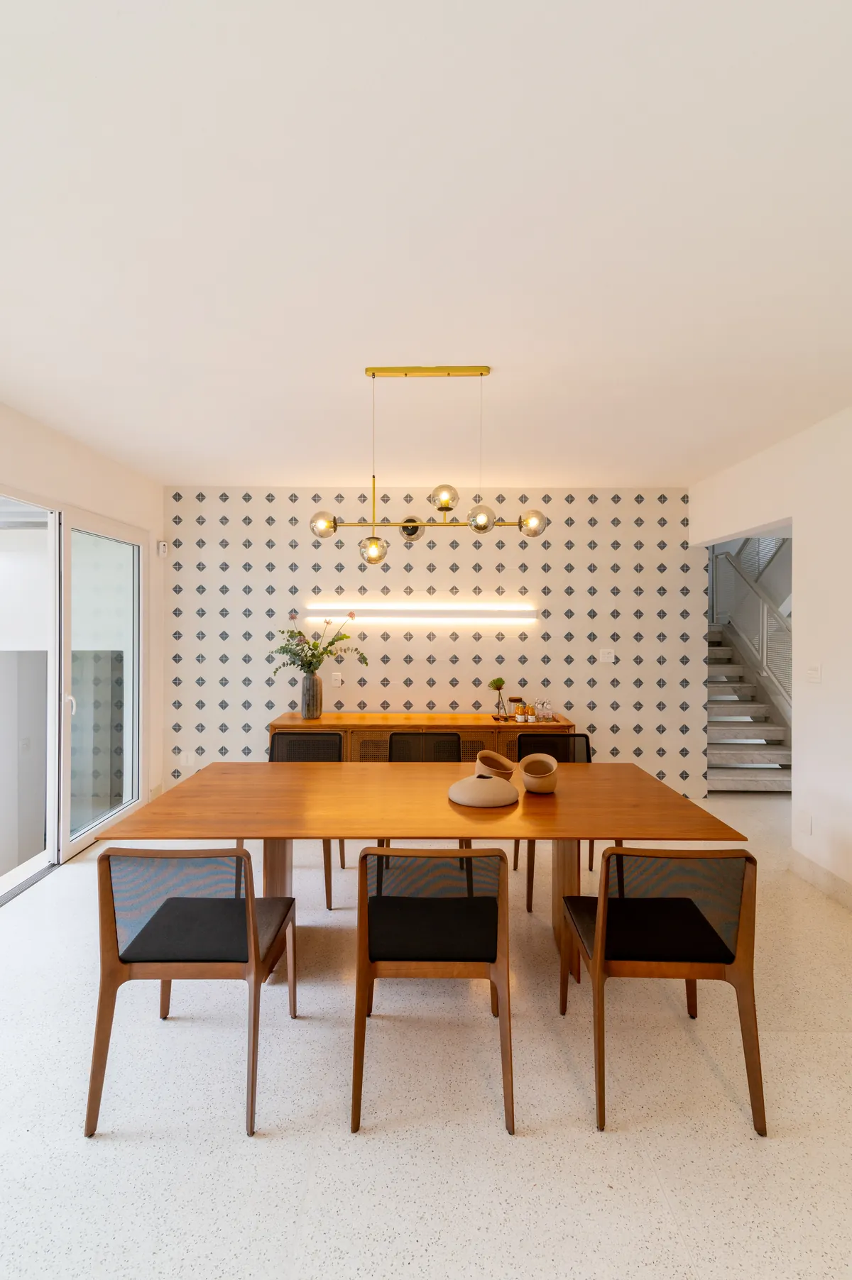Sala de jantar com mesa de madeira diante de parede de cobogó